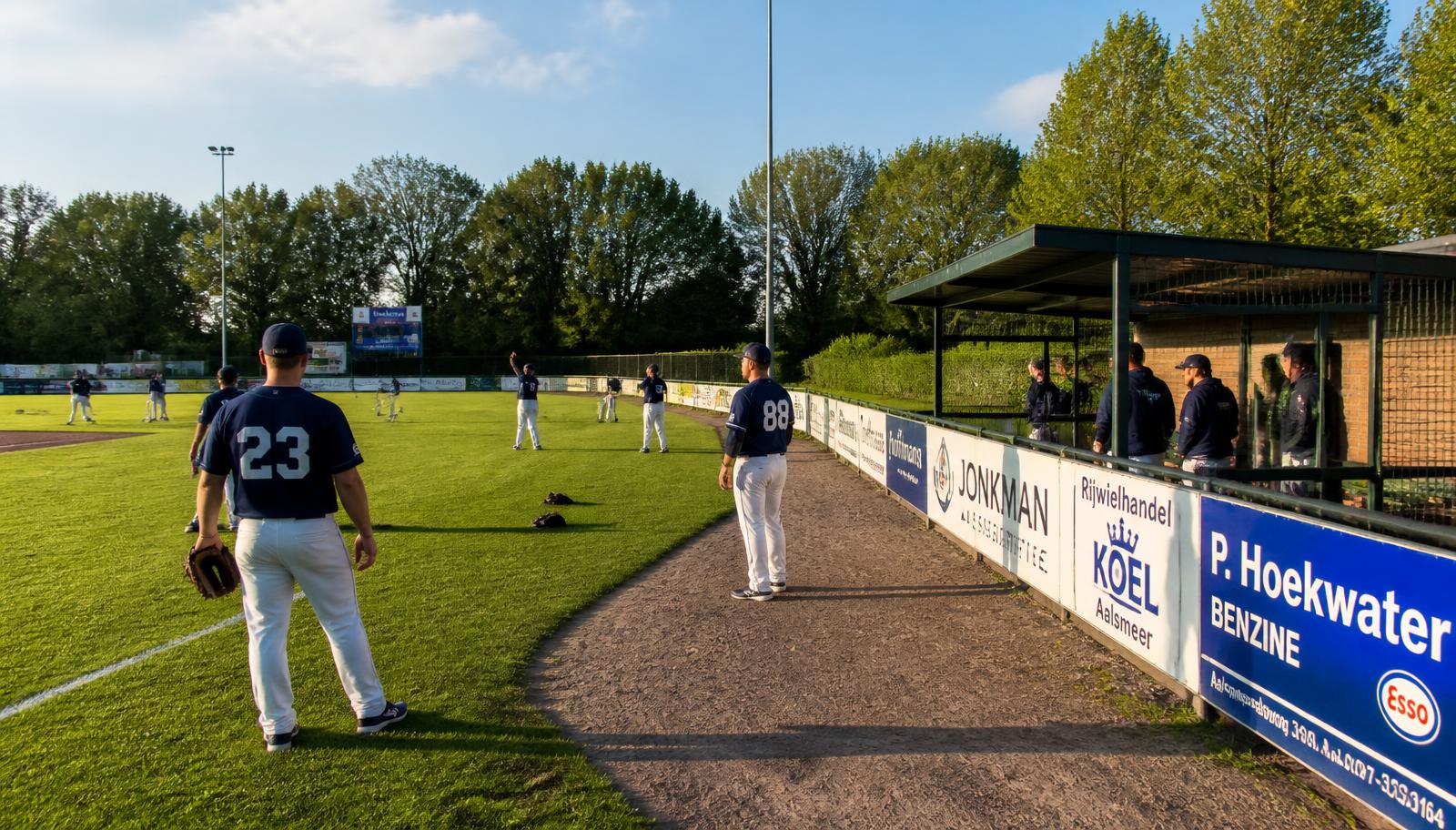 Spelers van The Braves warmen op langs het veld met reclameborden